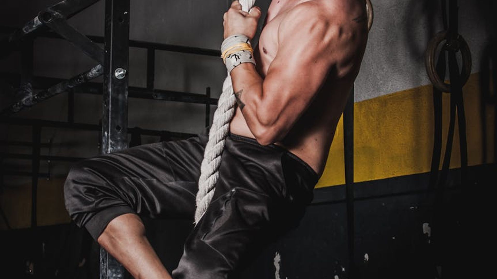 Athletic man performing a focused strength exercise in dark gym